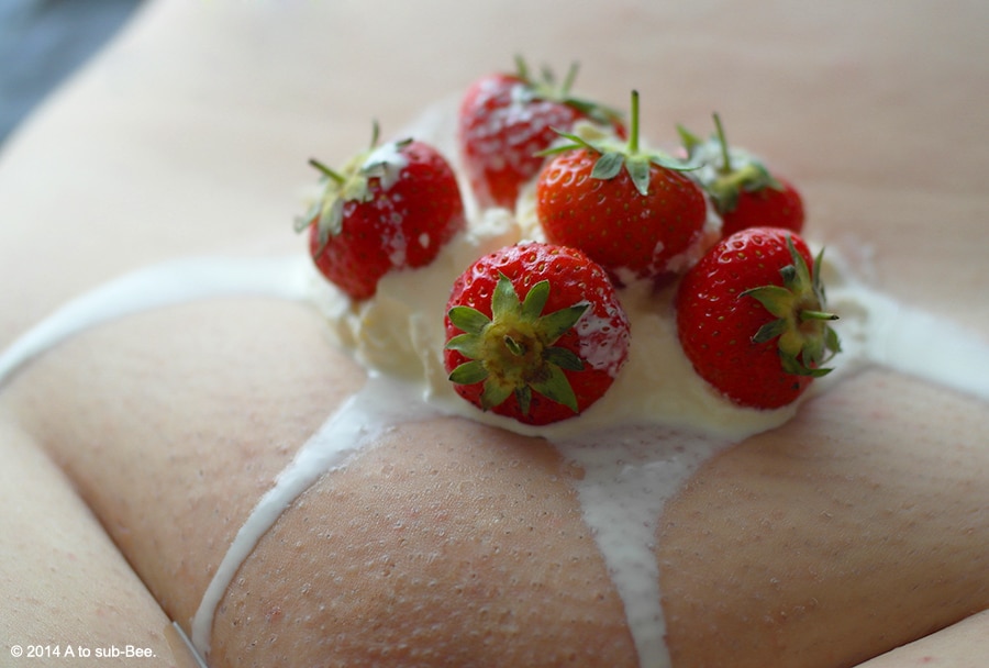 Bee naked with strawberries and cream on their stomach