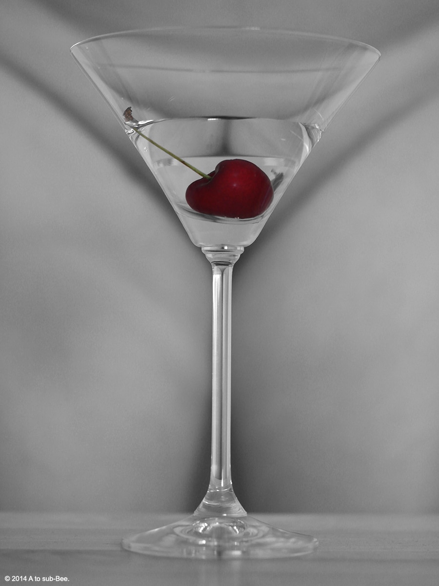 Bee starding naked behind a martini glass containing a cherry
