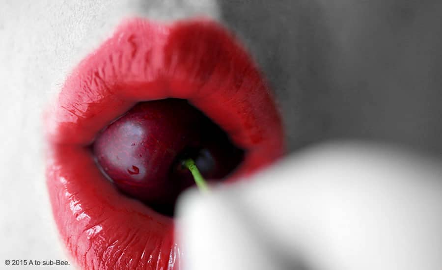 Bee's bright red lips wrapped around a succulent cherry enjoying its taste.
