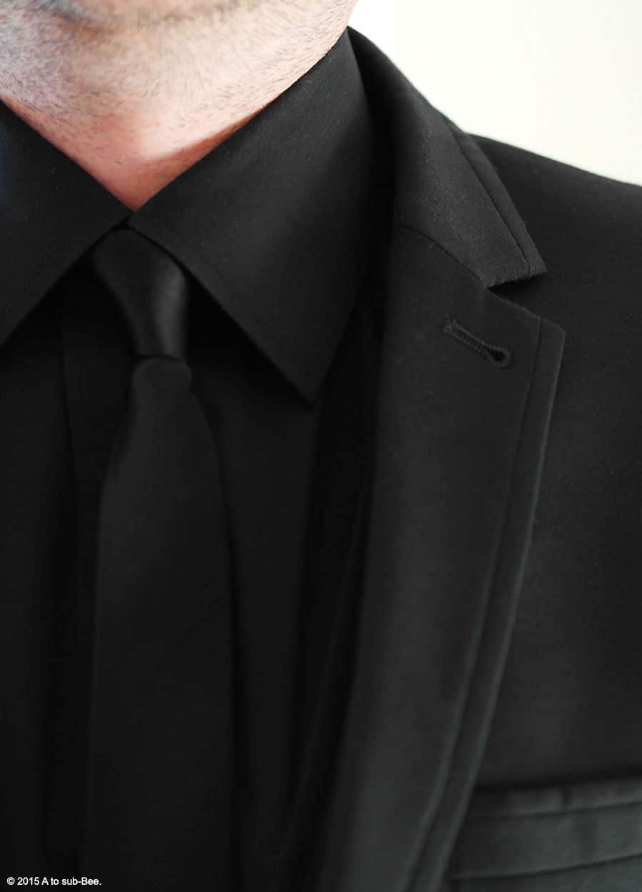 An image of the Keeper wearing a black suit, shirt and tie