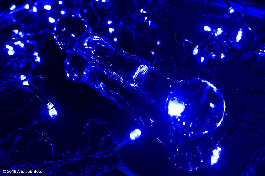 A glass dildo on a mirror lit with blue coloured fairy lights