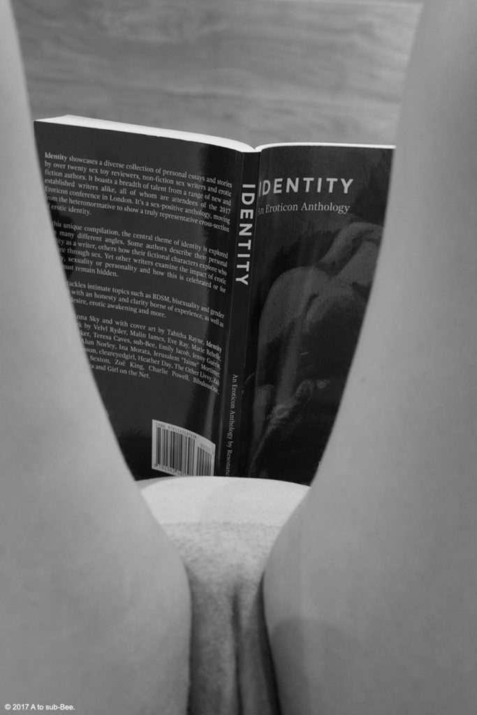 An image of Bee naked taken from between their legs as they read the Anthology called Identity