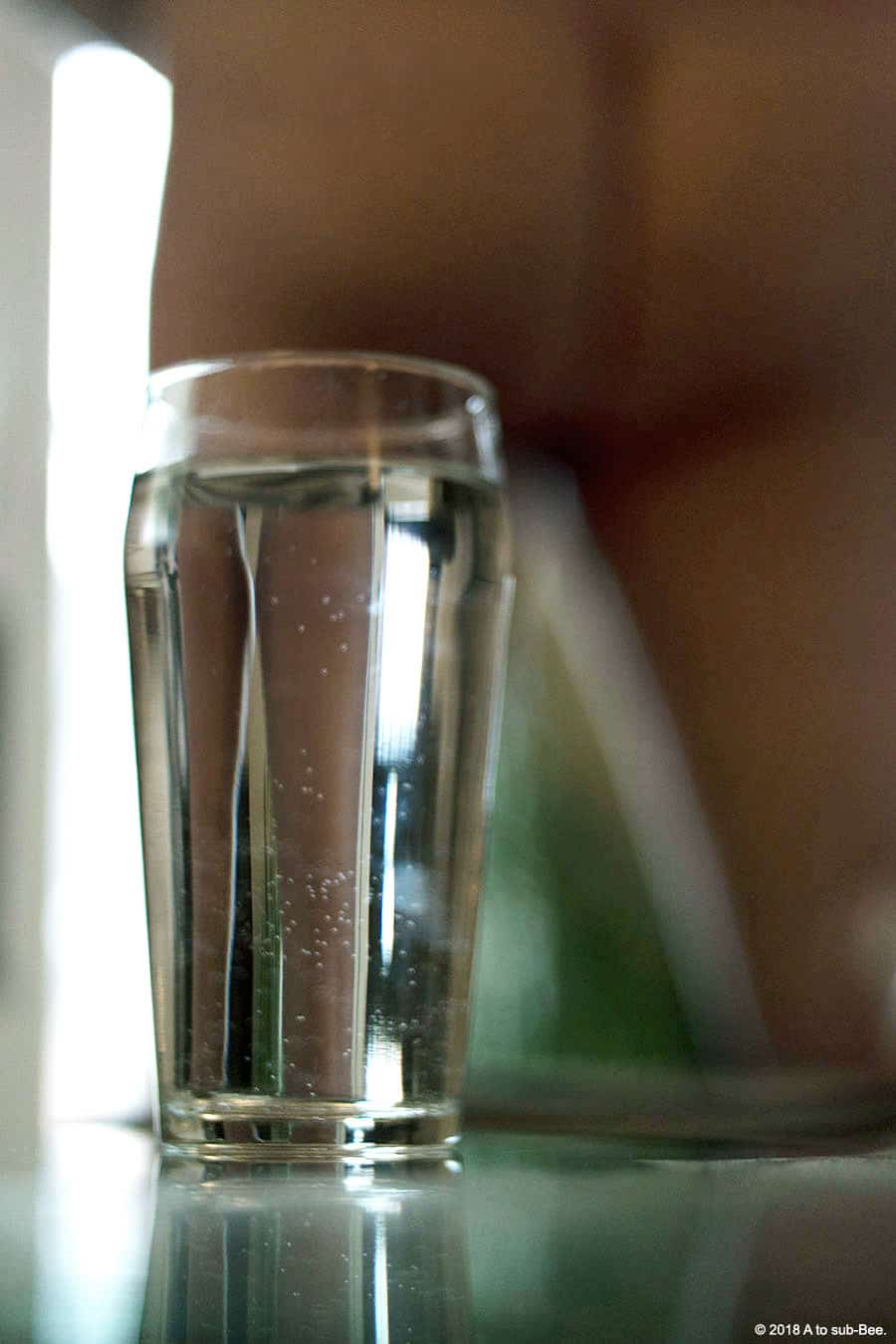 An image of Bee's bottom with a glass of water hiding one leg but through the glass you see Bee's legs