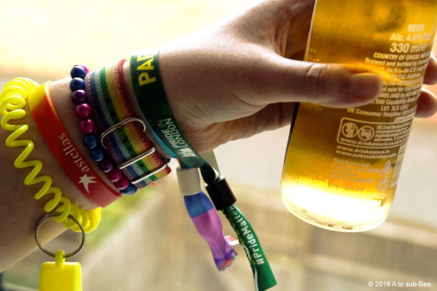 Bee drinking a well deserved beer after Pride wearing all the wristbands