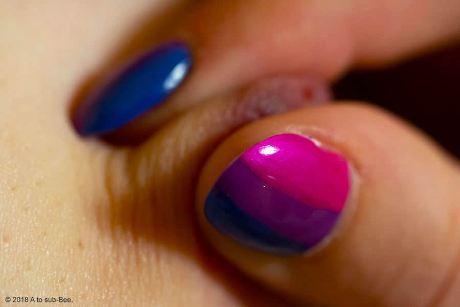 Bee pinching their nipple with her nails painted with the Bi flag colours