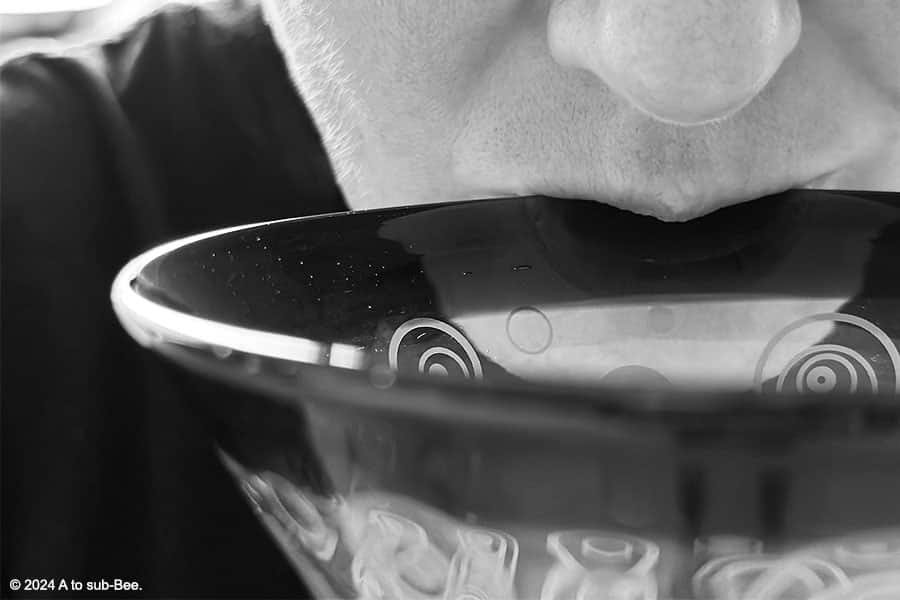 A black and white close up of a person drinking out of a cocktail glass