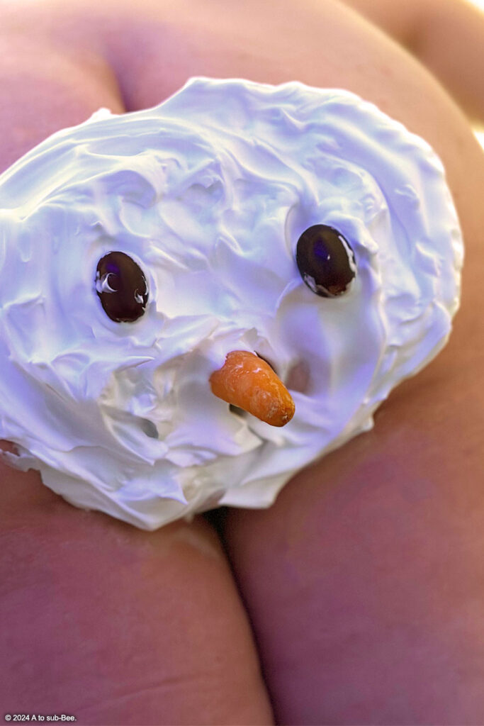 A snowman on a persons arse, crafted out of shaving cream, with grapes for eyes and a carrot nose