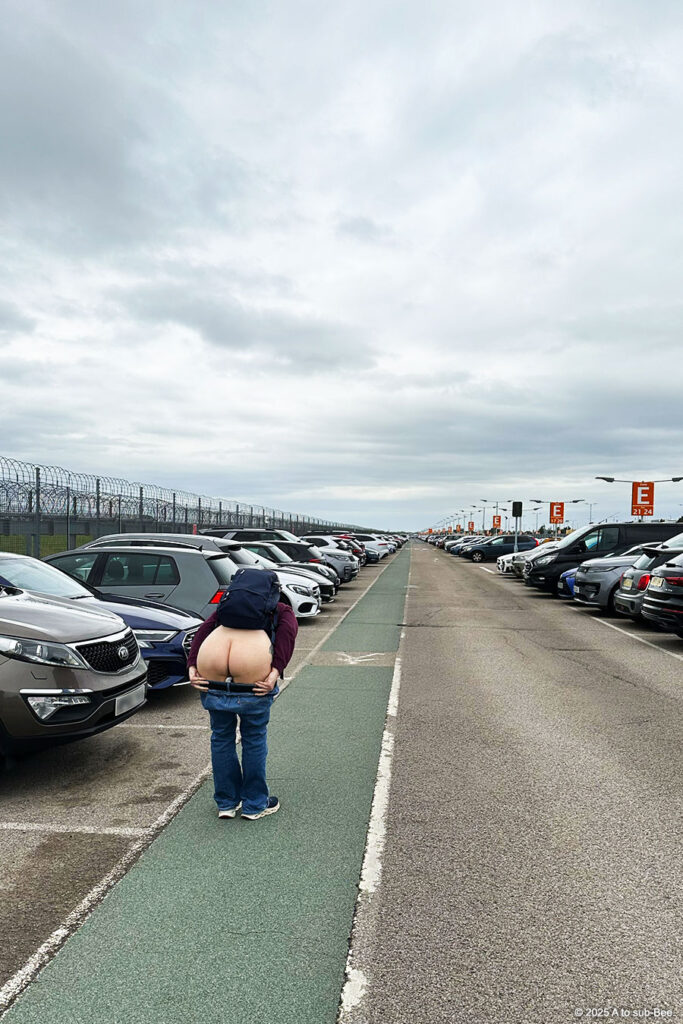 Image of a person bending over and exposing their arse in a big airport car park