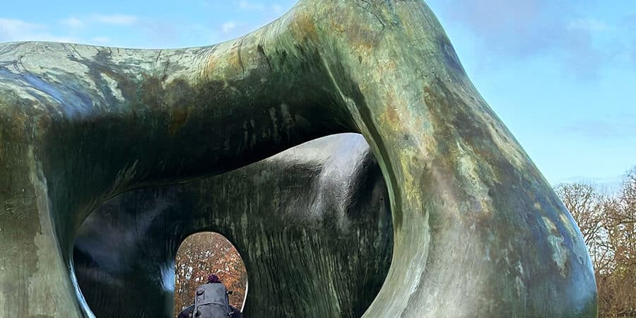 A person stood in the middle of a sculture, that looks like a wobbly ring, showing their bare bottom.